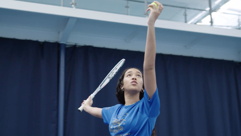A student hitting a ball with a tennis racket.