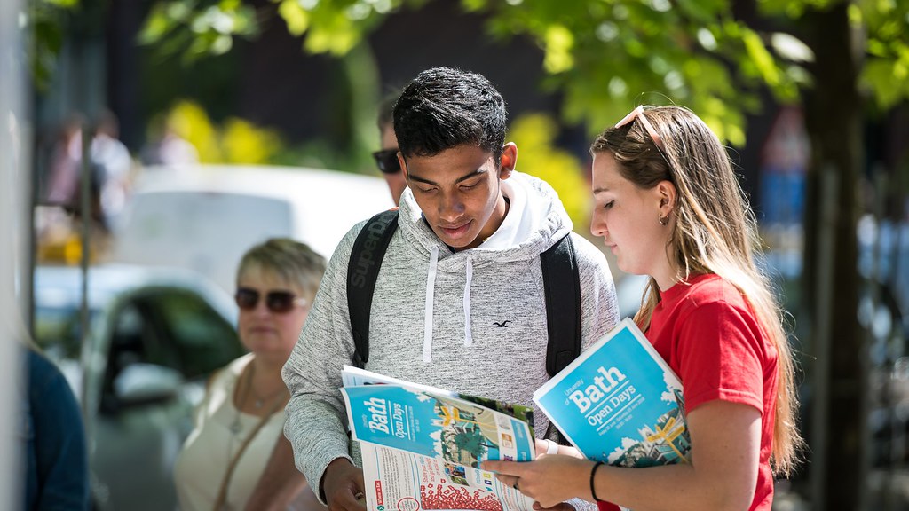 A visitor and a student ambassador looking at the Open Day guide on campus