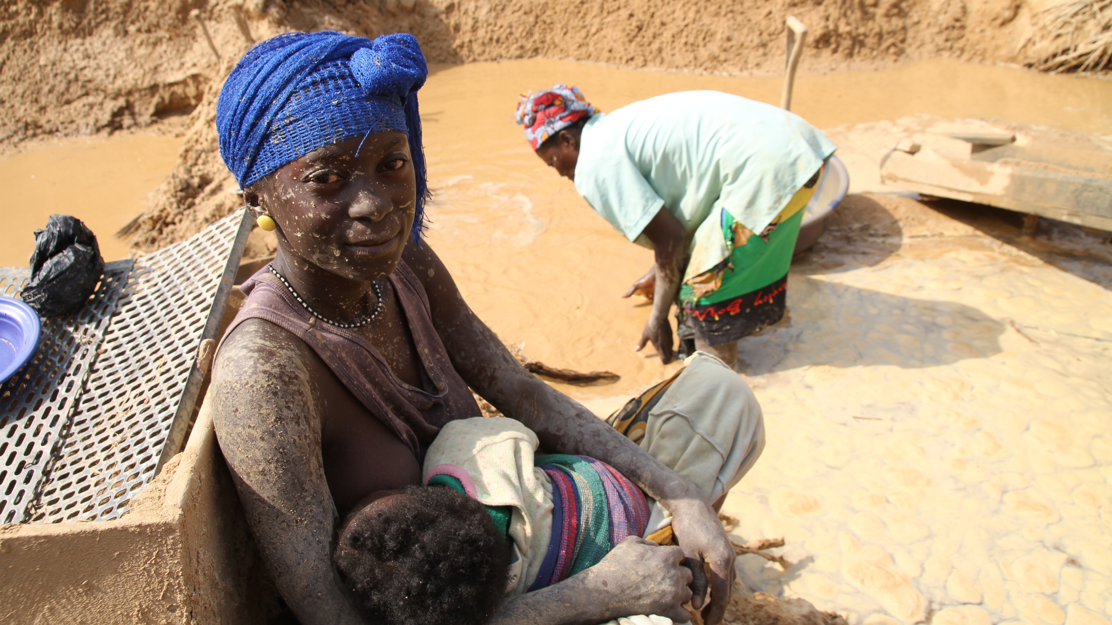 一位女士坐在泥矿里给她的孩子喂奶