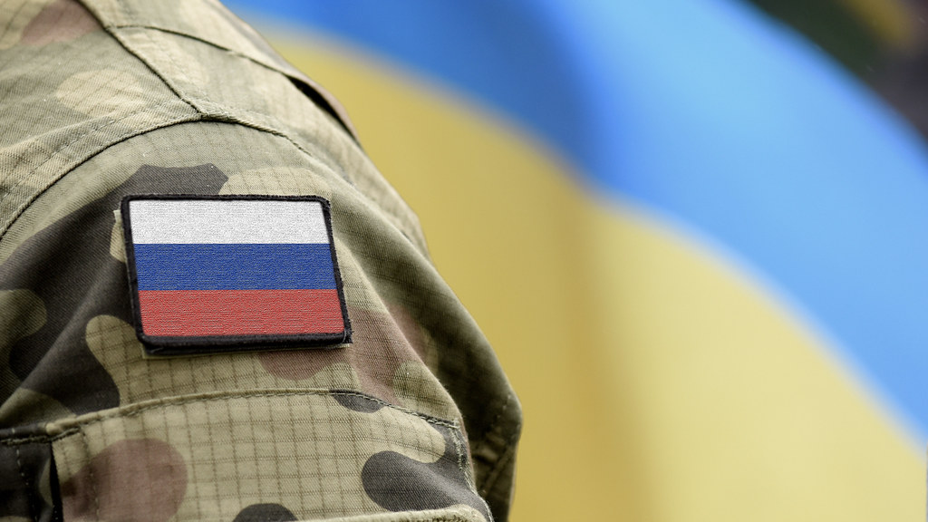 俄罗斯士兵身后举着乌克兰国旗.