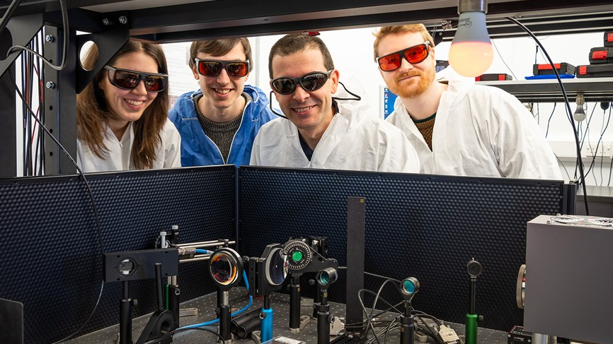 研究人员戴着紫外线眼镜站在实验光学设备后面