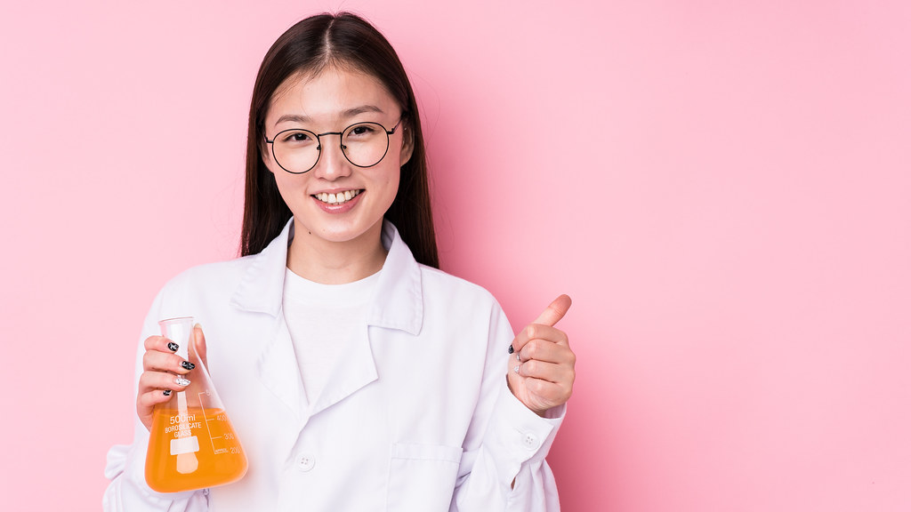 年轻的女科学家在实验室里拿着一个烧瓶，做一个大拇指