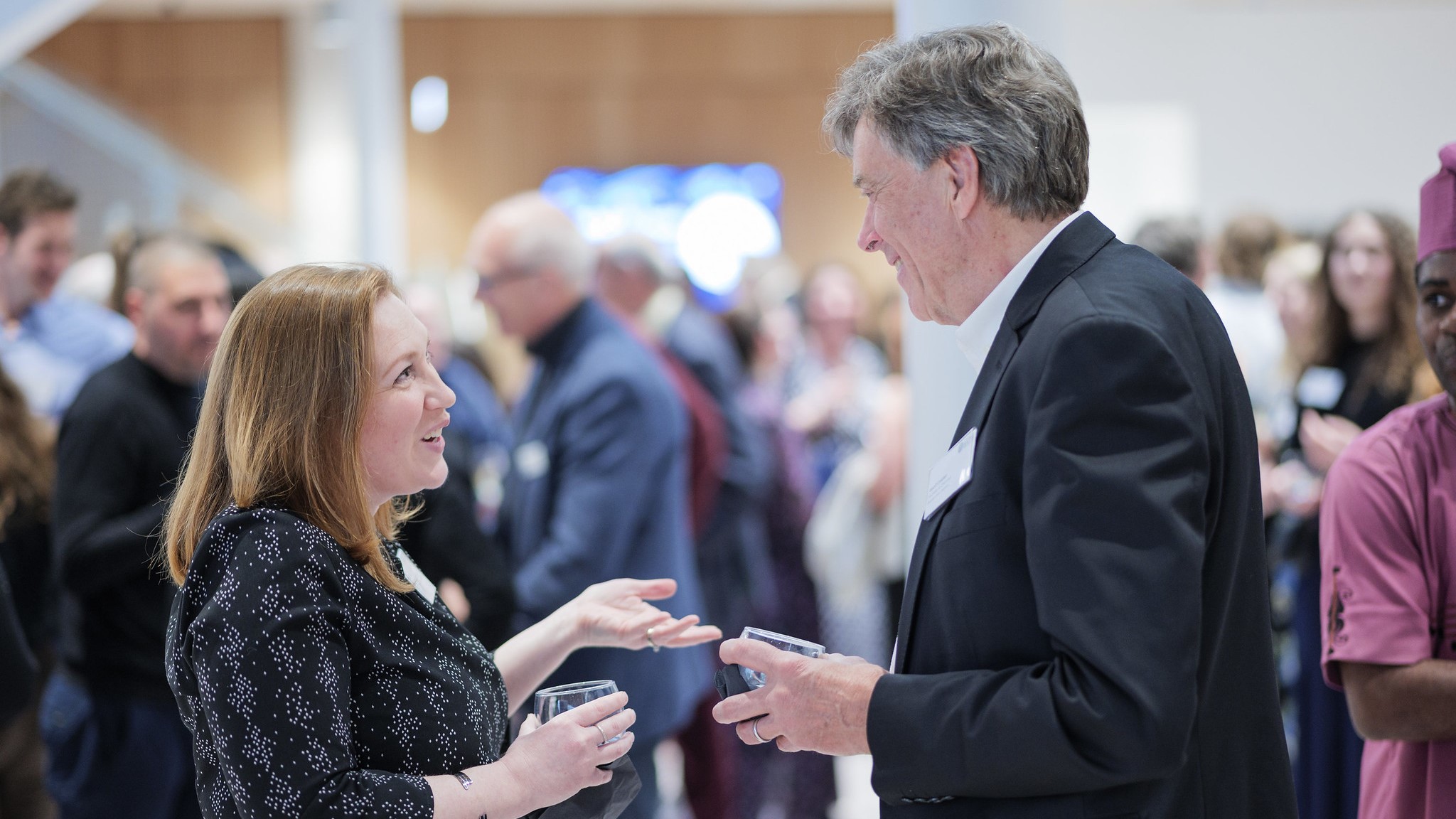 A smartly dressed man and a woman in conversation at an event