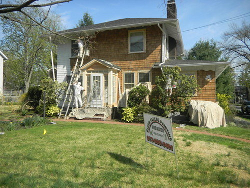 Workers applying exterior paint on a house in Maplewood, New Jersey, highlighting the significance of professional painting techniques for longevity in humid climates.
