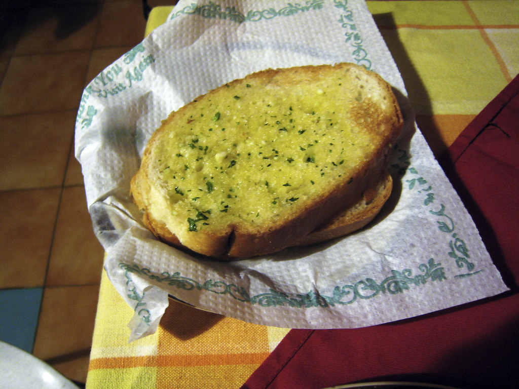 Garlic bread served on a white paper 