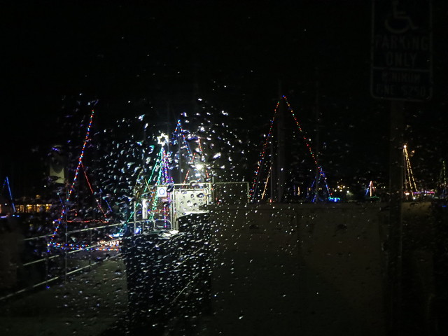 Christmas lights on sail boats through rainy window