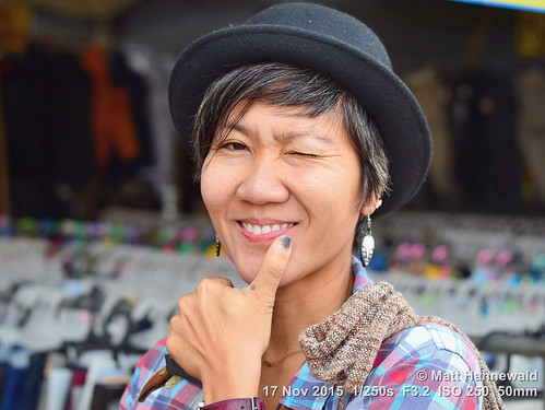 portrait smiling travel tourism market bowlerhat dropearrings teeth bokeh primelens woman female cultural character posing consent relationship emotion adult authentic closeup street bodylanguage gesture eyes asia matthahnewaldphotography face facingtheworld chiangdao horizontal head hand nikond3100 outdoor thailand thai 50mm hat expression northern headshot flirting nikkorafs50mmf18g threequarterview 4x3ratio 1200x900pixels resized lookingatcamera colour colourful person