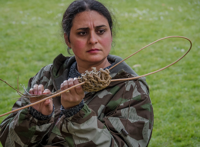 A girl in the process of weaving willow rods into the shape of a dragonfly at Downton Cuckoo Festival in Wiltshire