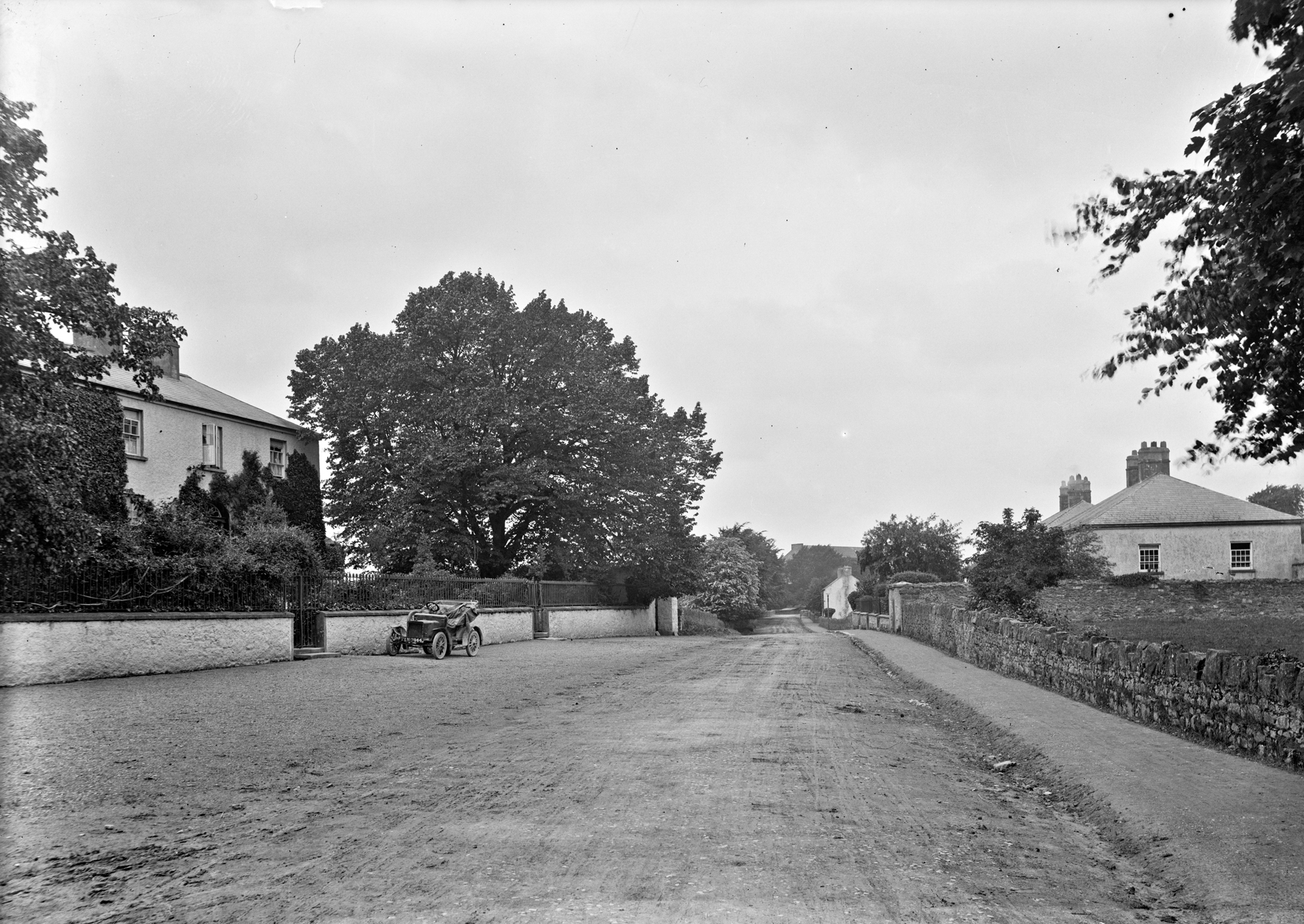 Roadway showing motor car parked outside house, Mountmellick, Co. Laois