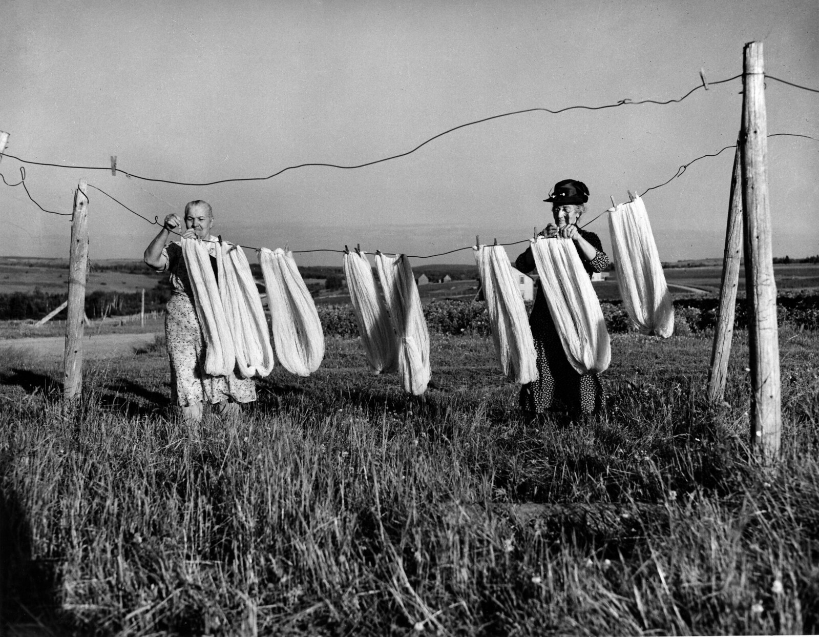 Two women airing wool on a line before spinning