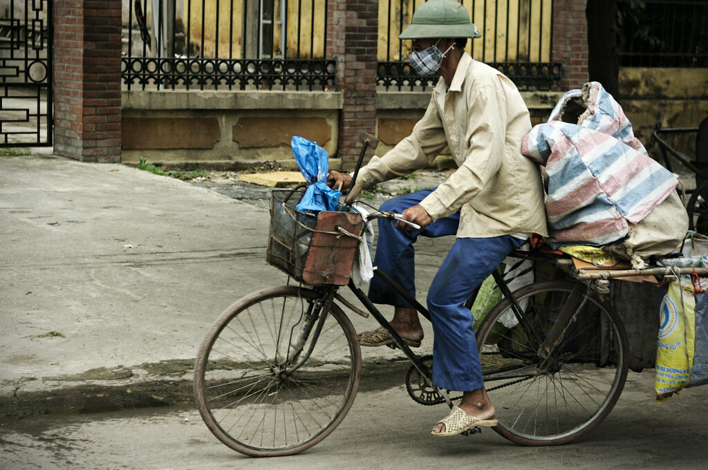 Man wearing a North Vietnamese Pith Helmet riding a bicycl… | Flickr