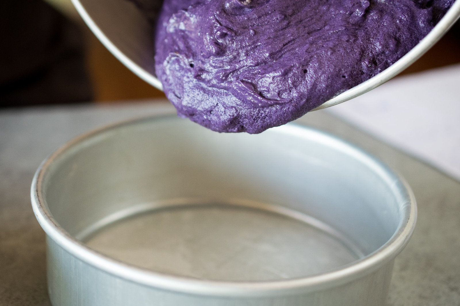 pouring the purple cake batter into the pan