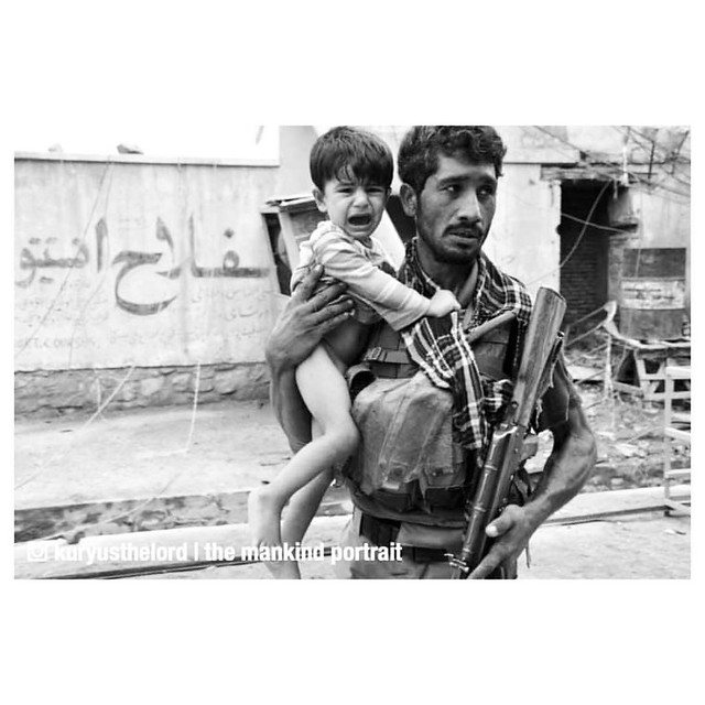 An Afghan soldier carries a crying child away from a recent explosion - Afghan War (c. 2001-2014)