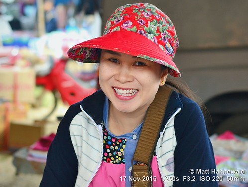 portrait smiling travel tourism market ethnic hat primelens woman female cultural character posing consent relationship emotion adult authentic closeup street eyes asia matthahnewaldphotography face facingtheworld chiangdao horizontal head nikond3100 outdoor thailand thai 50mm seveneighthsview expression northern headshot sun visor red nikkorafs50mmf18g 4x3ratio 1200x900pixels resized lookingatcamera colour colourful person