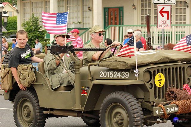 US WWII soldiers and boy ride in Jeep.