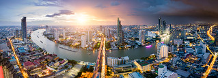 Aerial view of Bangkok skyline and skyscraper with light trails on Sathorn Road center of business in Bangkok downtown. Panorama of Taksin Bridge over Chao Phraya River Bangkok Thailand at sunset.