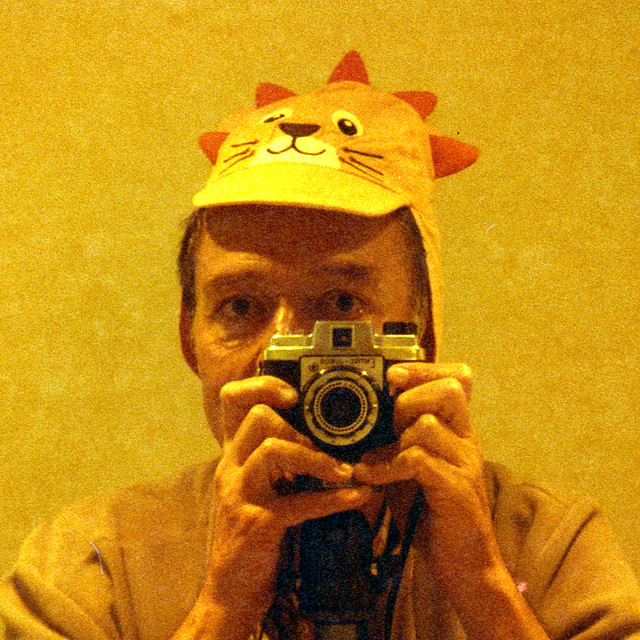 reflected self-portrait with Empire Junior camera and lion hat (cropped)