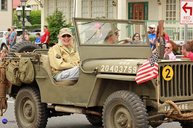 Couple in WWII outfits ride in Jeep.