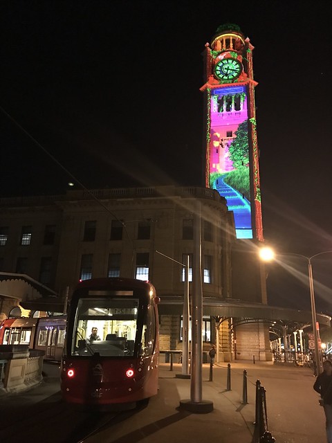 A vivid clock tower and a tram