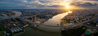 Aerial view panorama of Bhumibol suspension bridge cross over Chao Phraya River in Bangkok city with car on the bridge at sunset sky and clouds in Bangkok Thailand.