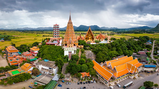 Aerial view of Wat Tham Sua Temple with rice fields in Kanchanaburi Province, Thailand.