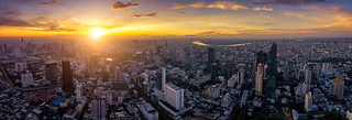 Aerial view of Bangkok skyline panorama and skyscraper with light trails on Silom road center of business in capital. Modern city and BTS skytrain with Chao Phraya river at Bangkok Thailand on sunrise