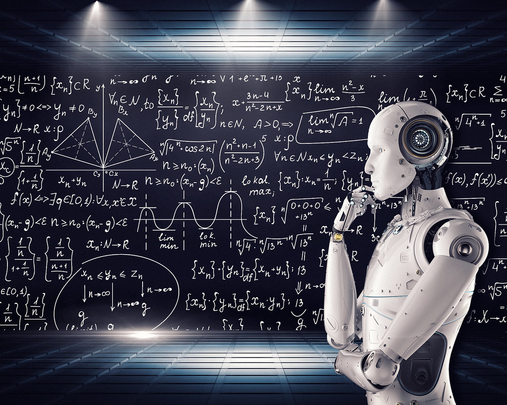 a white robot stands sideways before a blackboard covered with mathematical equations