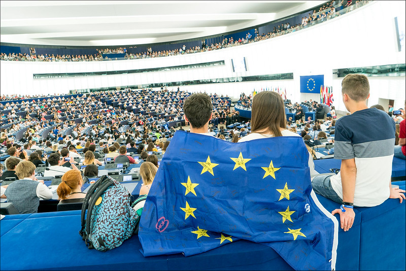 Junge Menschen mit einer EU-Flagge nehmen an einer Veranstaltung im Europäischen Parlament teil