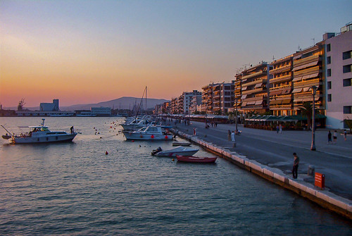 volos greece greek grecian sunset sun boat water front pier mountain boardwalk buildings architecture sky blue red orange yellow europe