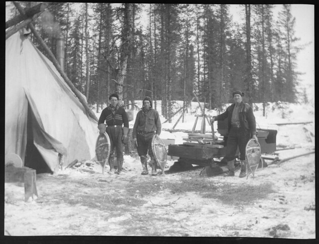 Hommes tenant des raquettes à neige devant une tente