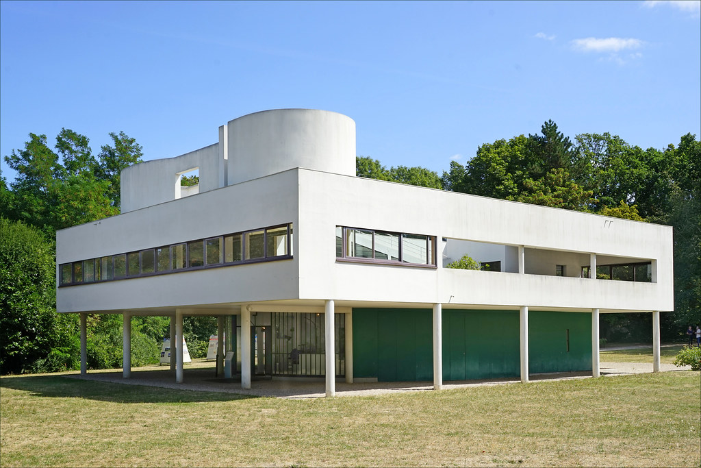 La Villa Savoye de Le Corbusier (Poissy, France): A white building with a rectangular top, an awning that goes all the way around the building and long rectangular windows. 