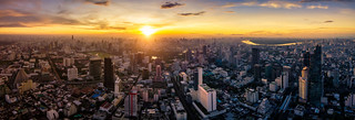 Aerial view of Bangkok skyline panorama and skyscraper with light trails on Silom road center of business in capital. Modern city and BTS skytrain with Chao Phraya river at Bangkok Thailand on sunrise