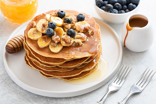 Stack of pancakes with banana, blueberries, walnuts, honey and caramel sauce