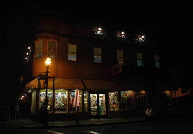 American flag hangs in the window, night, Cunha’s Country Grocery & Second Floor Emporium, Half Moon Bay, California, USA
