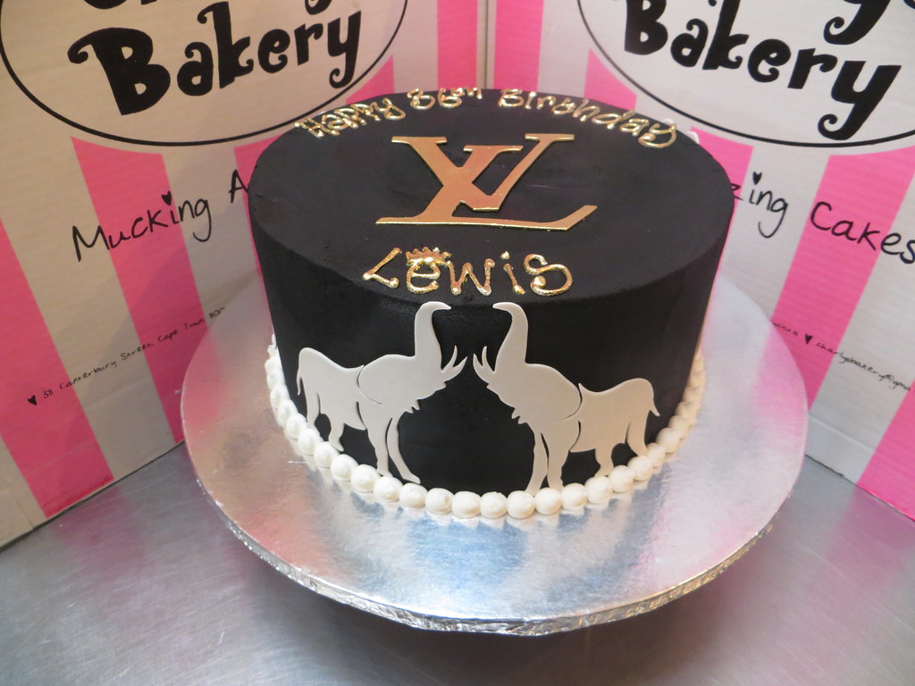 Black and white cake with gold Louis Vuitton logo on top a…