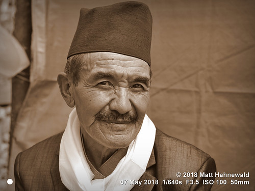 matthahnewaldphotography facingtheworld character head face eyes catchlights expression moustache cap hat shawl bhaadgaauletopi blackcap respect dignity travel socialevent ethnic local traditional cultural wedding celebration village tarkeghyang helambu himalayas nepal asia asian nepali sherpa hyolmo male elderly man backdrop nikond3100 primelens nikkorafs50mmf18g 50mm street portrait closeup threequarterview outdoor sepia vignette photoshop postprocessing editing posingcamera wellgroomed manly serious trekking hiking clarity wrinkles person conceptual consensual lookingatcamera monochrome headshot