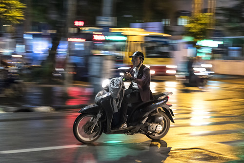 hanoi vietnam asia town city night scooter moped driving man driver road reflection rain texting panning landscape outdoor fast speed