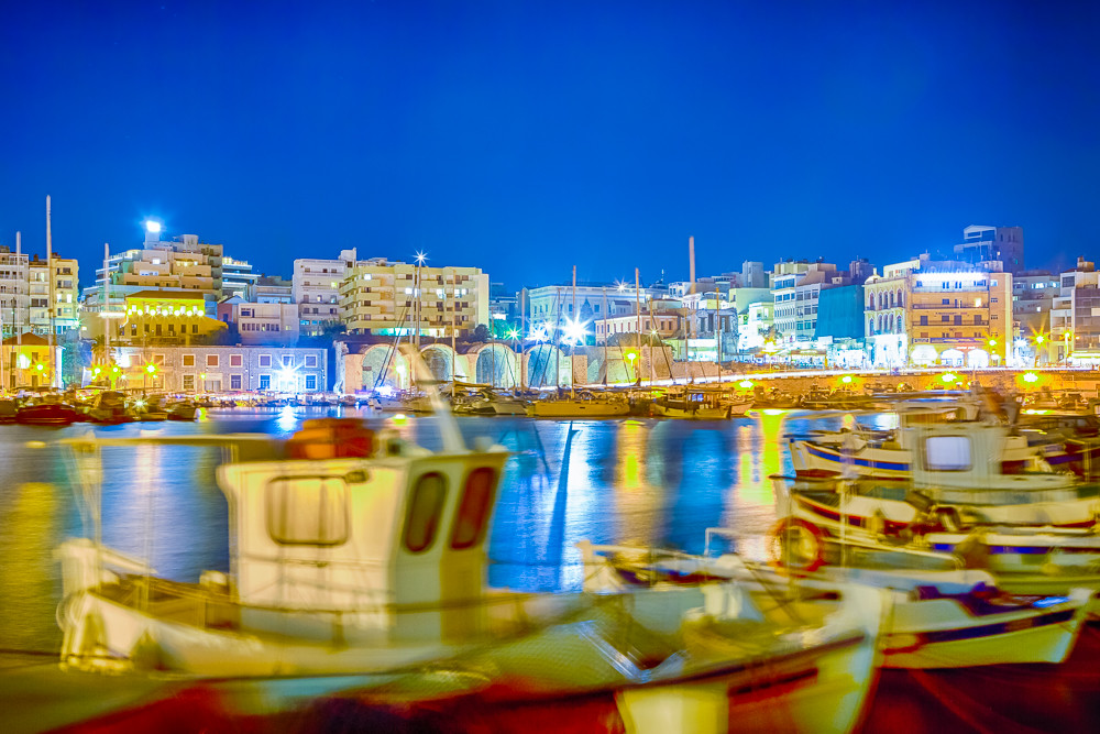 Panorama of Old Venetian Harbour with Lines of Ships and Boats At Blue Hour in Heraklion City in Greece. Blurred Motion of The Boats Due to Wind and Sea Waves On Foreground.