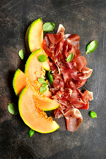 Sliced melon and jamon or prosciutto with bottle of red wine.Top view.