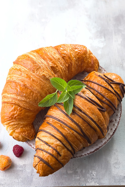Fresh tasty croissants with berries on white stone background