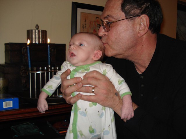 Grandpa holding grandson in front of the Hanukah candles