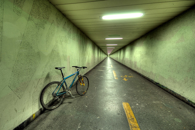 a green bike in the green tunnel; waiting for something in an other color
