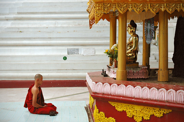 Monk sitting in front of a buddha statue - Shwedagon pagoda - Yangon - Myanmar