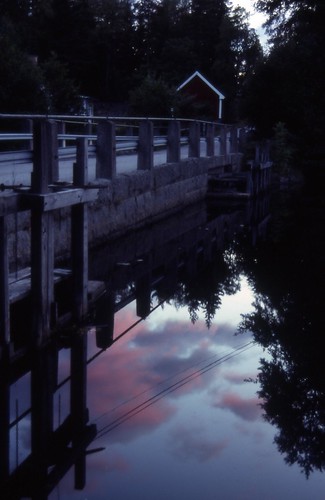 Dammluckorna i Kaxgärde by N Stjerna, sunset bridge house purple sky clouds water reflection dark forrest trees stone nybro småland sweden
