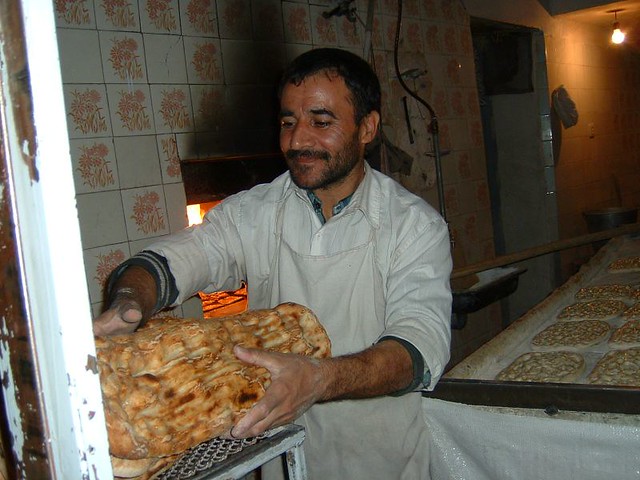Proud baker removing fresh-baked barbary bread