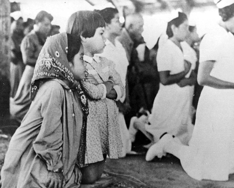 Two girls kneel with the congregation as prayers are being lead by the techa.

Paul Carano/Micronesian Area Research Center (MARC)
