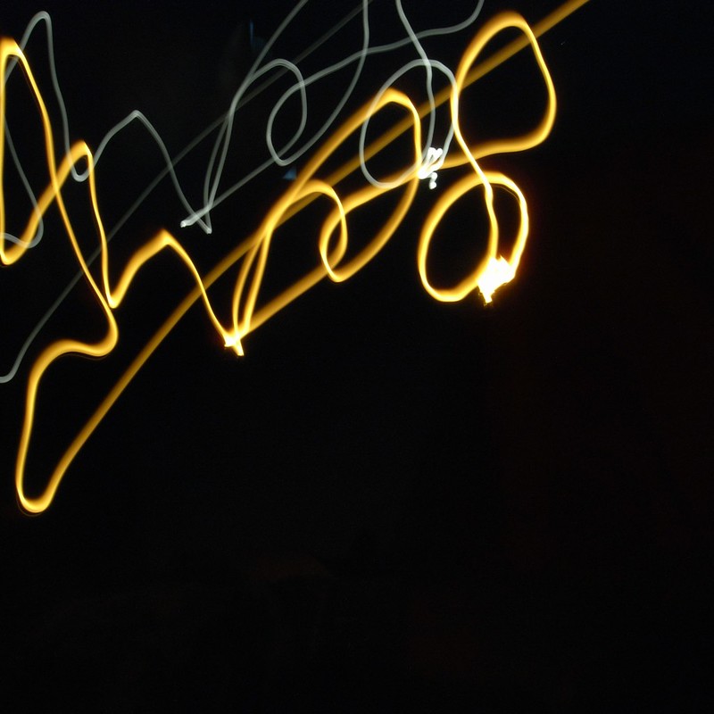 Black background with amber and white light swirls that look like writing.