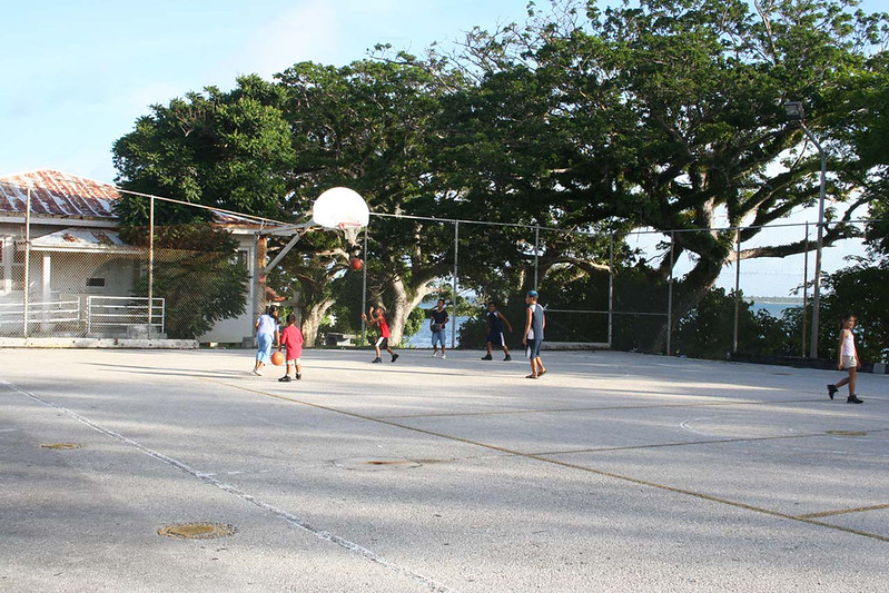 Kids play at a basketball court in the quiet southern village of Malesso’/Merizo. In the background is the Merlyn G. Cook School, an historic structure that stands beside the Malesso’ pier.

Nathalie Pereda/Guampedia