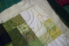 The three layers are now anchored together with overall stitching (the quilting).  Next task: cut the quilt free of the excess batting and fabric, then close off (bind) the edges.