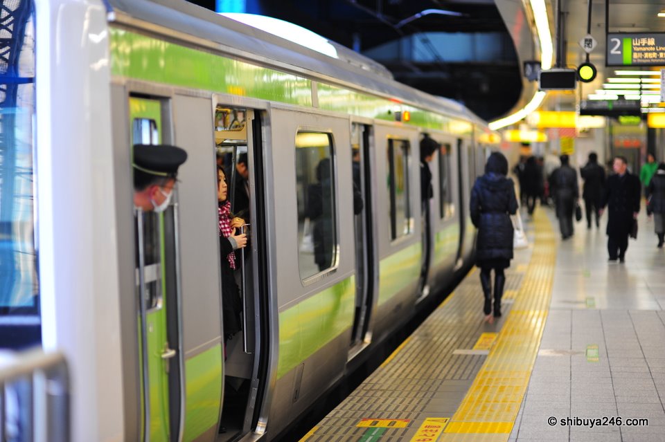 The train driver takes a peek out of his cab to see what is going on.